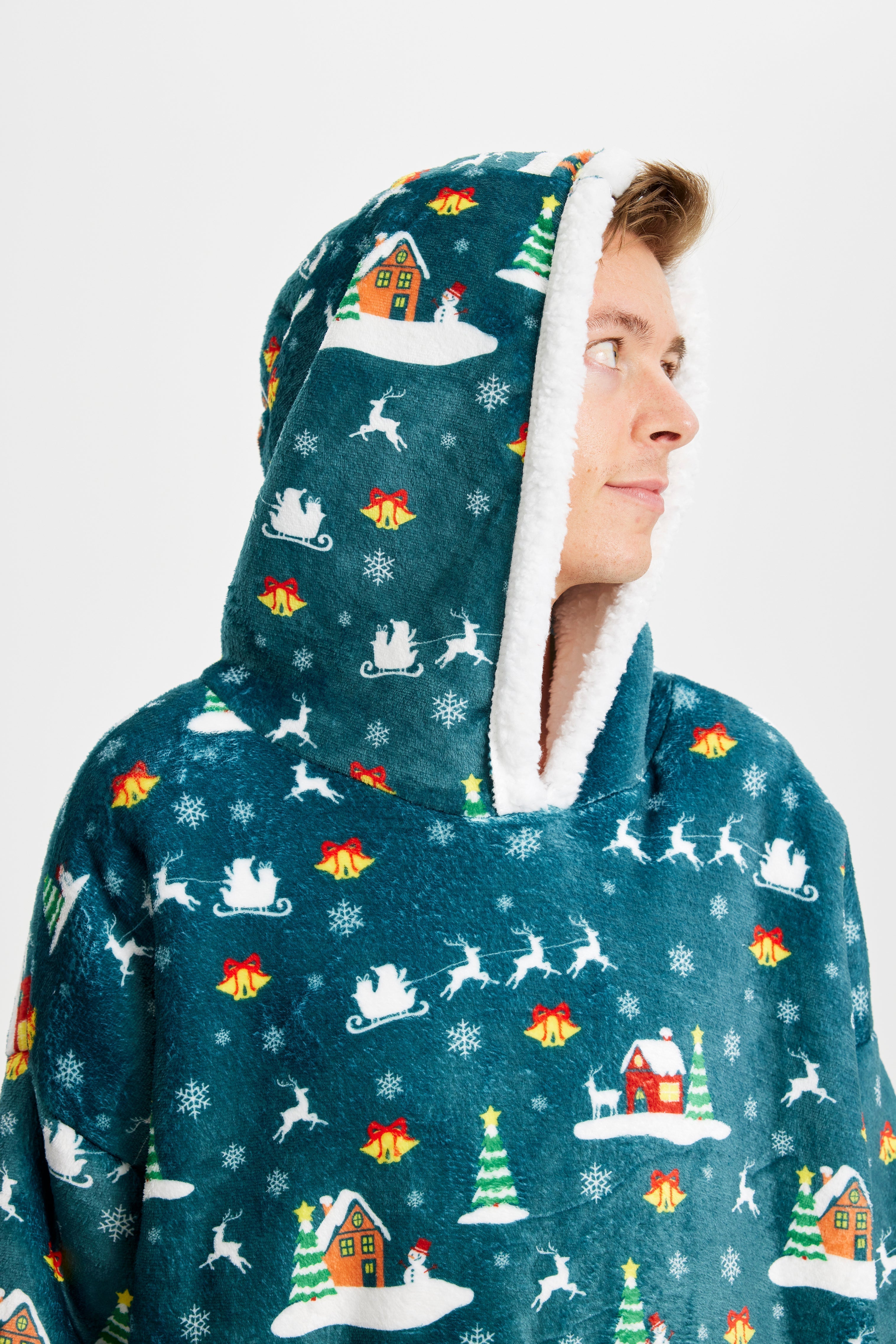 Un uomo che indossa una felpa natalizia verde guarda di lato.